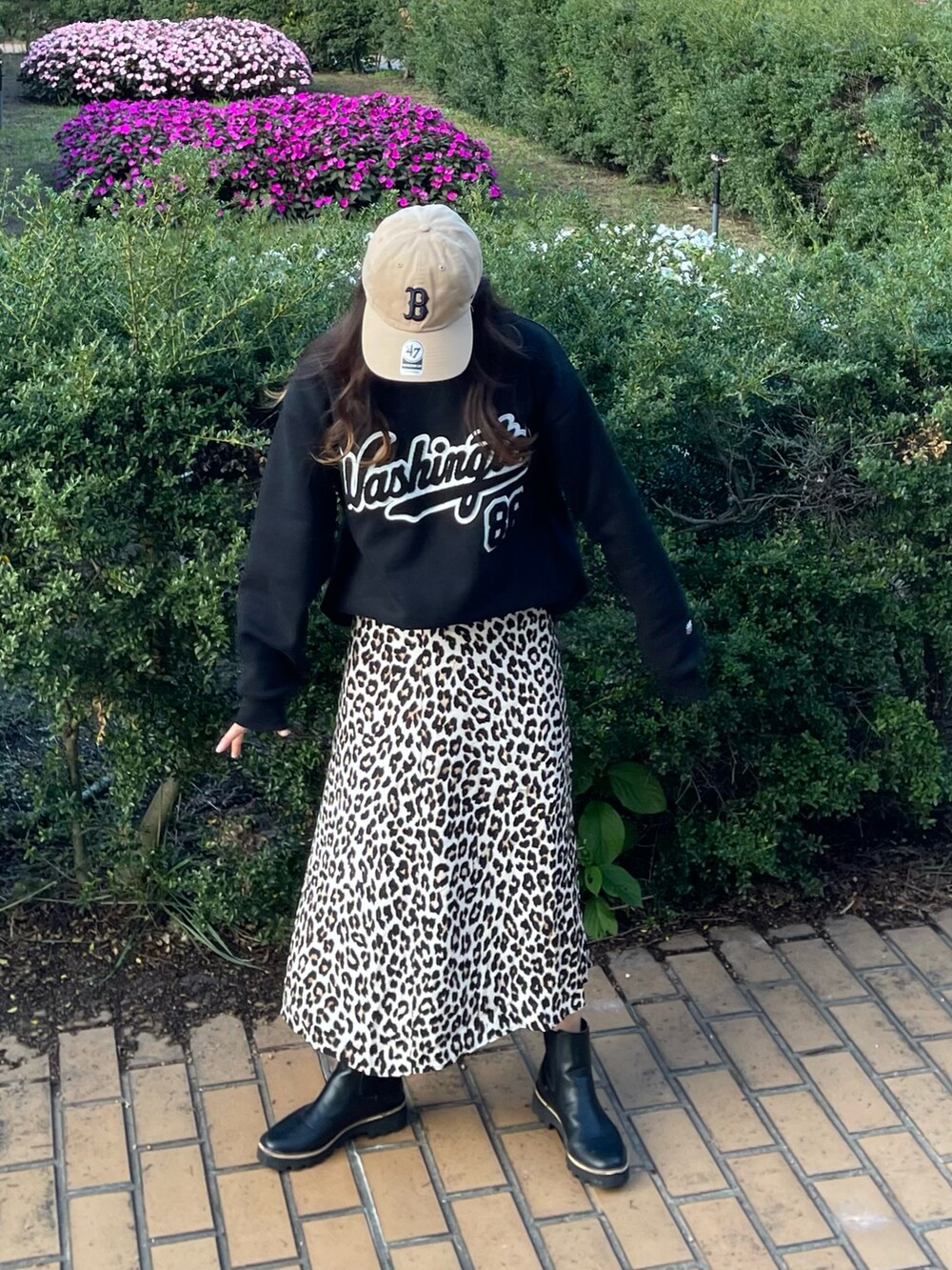 ベージュ系のスカート、ブラック系のスウェット、ブラック系のブーツを着用したレディースの秋コーディネートの2枚目の写真