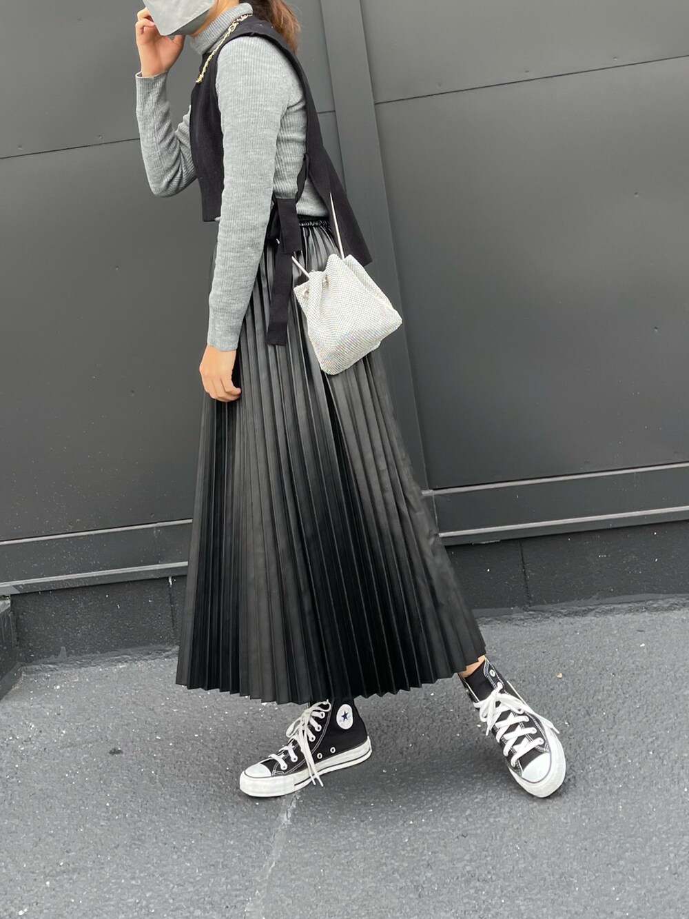 ブラック系のスカート、ブラック系のスニーカー、ブラック系のベストを着用したレディースの冬コーディネートの3枚目の写真