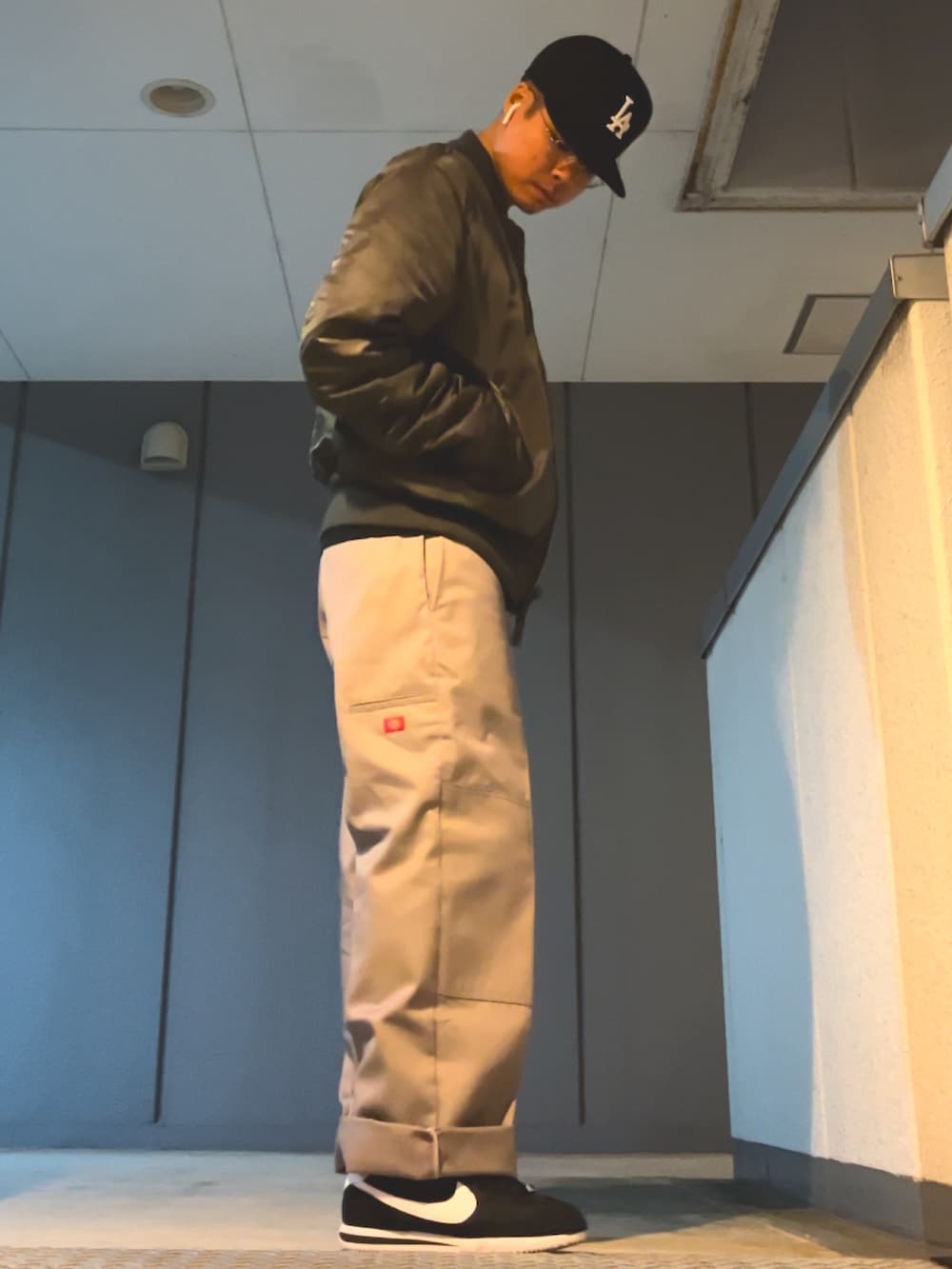 シルバー系のチノパンツ、ブラック系のスニーカー、グレー系のMA-1を着用したメンズの秋コーディネートの2枚目の写真