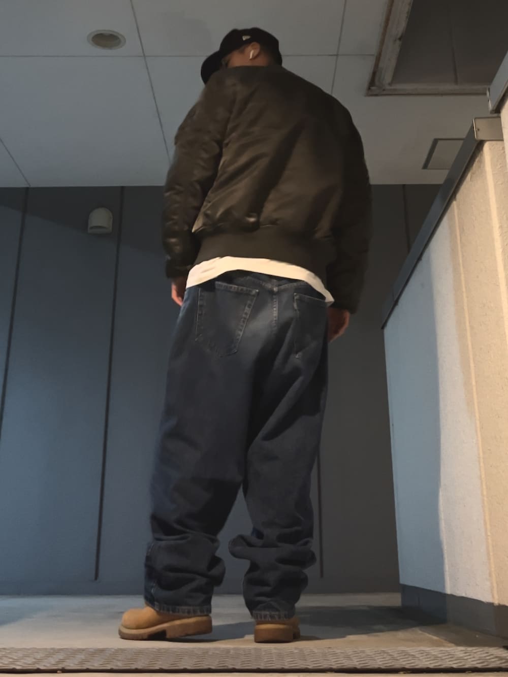 ブルー系のデニムパンツ、グレー系のMA-1、ブルー系のキャップを着用したメンズの秋コーディネートの2枚目の写真