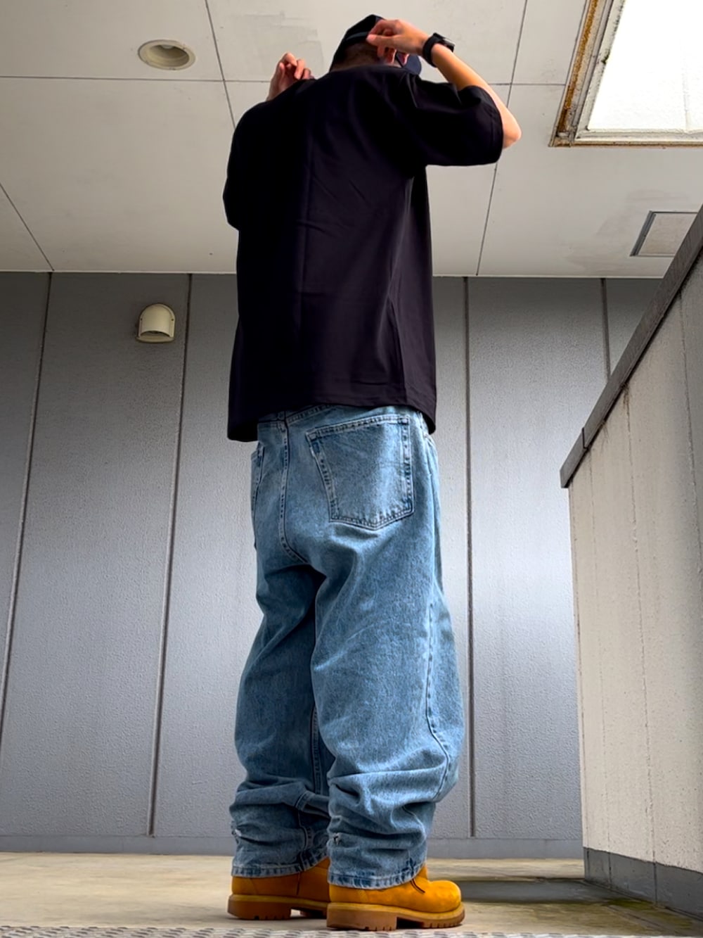 ブルー系のデニムパンツ、ブラック系のTシャツ/カットソー、イエロー系のブーツを着用したメンズの春コーディネートの2枚目の写真