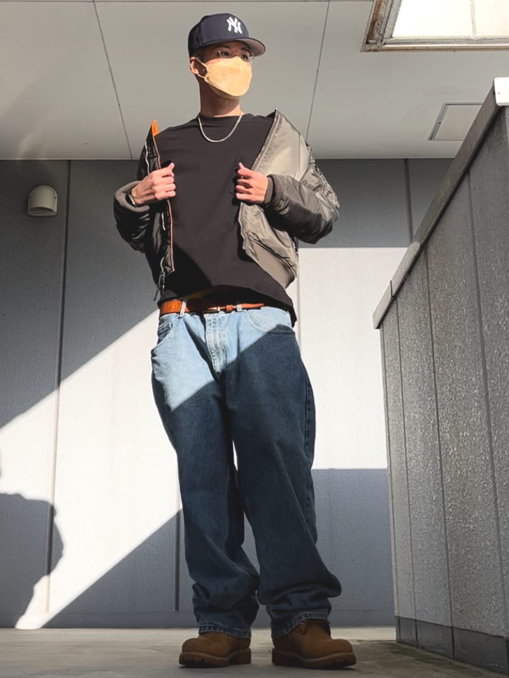 ブルー系のデニムパンツ、ブラック系のTシャツ/カットソー、イエロー系のブーツを着用したメンズの春コーディネートの3枚目の写真