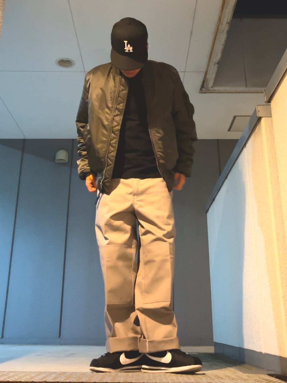 シルバー系のチノパンツ、ブラック系のスニーカー、グレー系のMA-1を着用したメンズの秋コーディネートの3枚目の写真