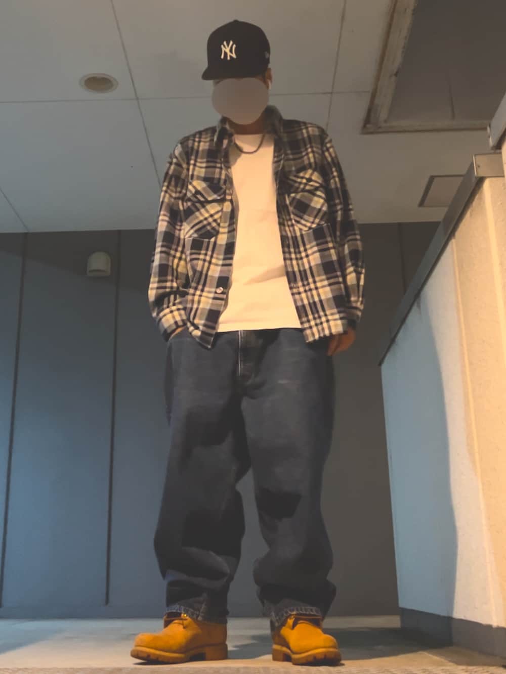 ブルー系のデニムパンツ、イエロー系のブーツ、ホワイト系のTシャツ/カットソーを着用したメンズの秋コーディネートの2枚目の写真