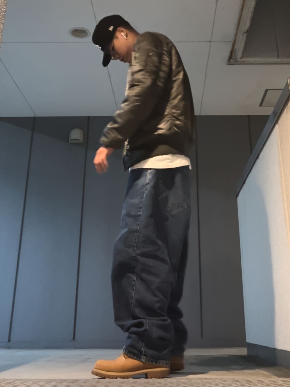 ブルー系のデニムパンツ、グレー系のMA-1、ブルー系のキャップを着用したメンズの秋コーディネートの3枚目の写真