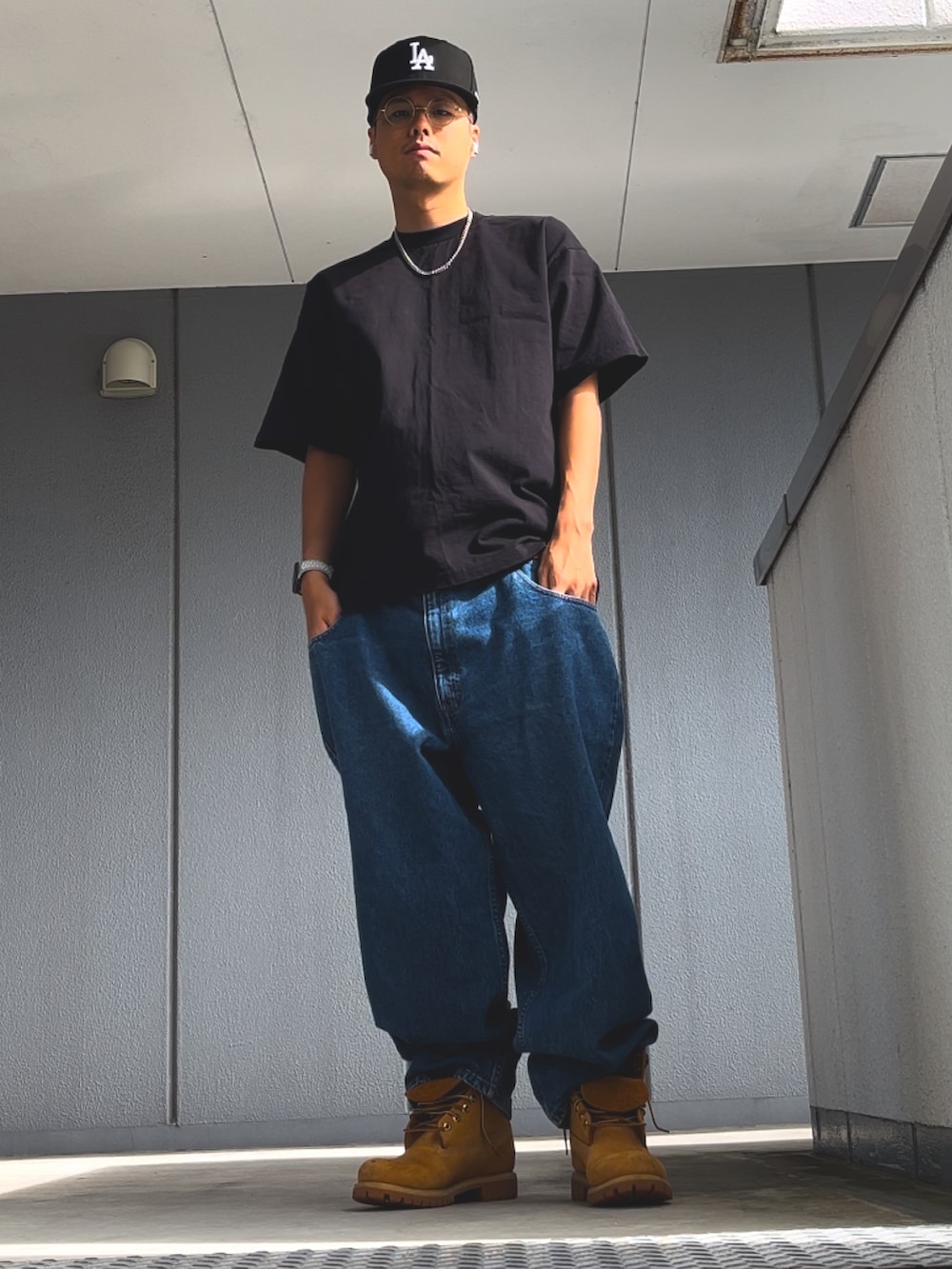 ブルー系のデニムパンツ、イエロー系のブーツ、ブラック系のTシャツ/カットソーを着用したメンズの秋コーディネートの2枚目の写真