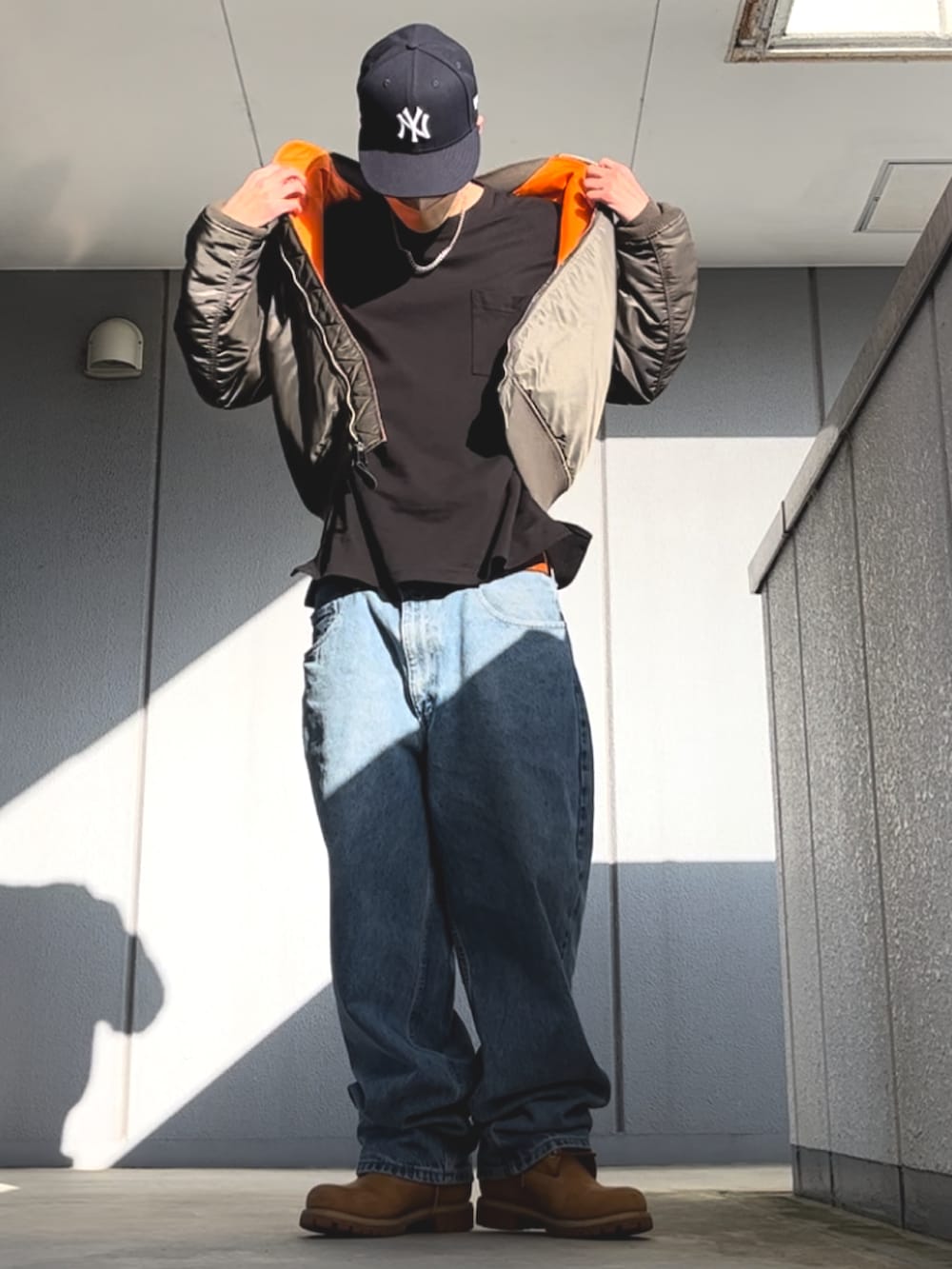 ブルー系のデニムパンツ、ブラック系のTシャツ/カットソー、イエロー系のブーツを着用したメンズの春コーディネートの4枚目の写真