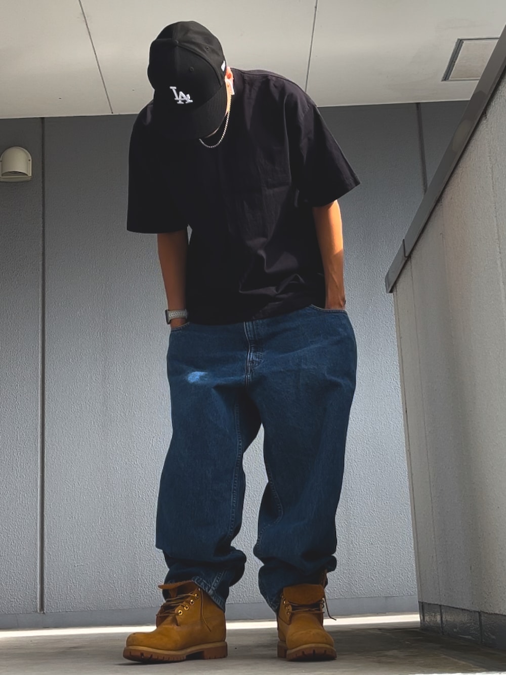 ブルー系のデニムパンツ、イエロー系のブーツ、ブラック系のTシャツ/カットソーを着用したメンズの秋コーディネートの3枚目の写真