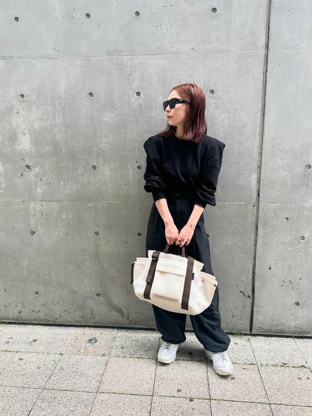 ホワイト系のトートバッグ、ブラック系のパンツ、ブラック系のサングラスを着用したレディースの夏コーディネートの2枚目の写真