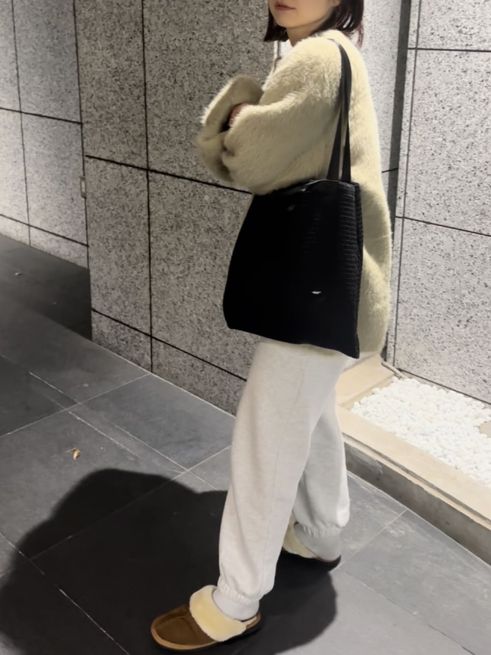 ブラック系のトートバッグ、ホワイト系のスウェットパンツを着用したレディースの冬コーディネートの2枚目の写真