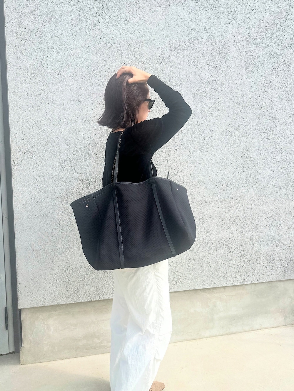 ブラック系のトートバッグを着用したレディースの秋コーディネートの2枚目の写真