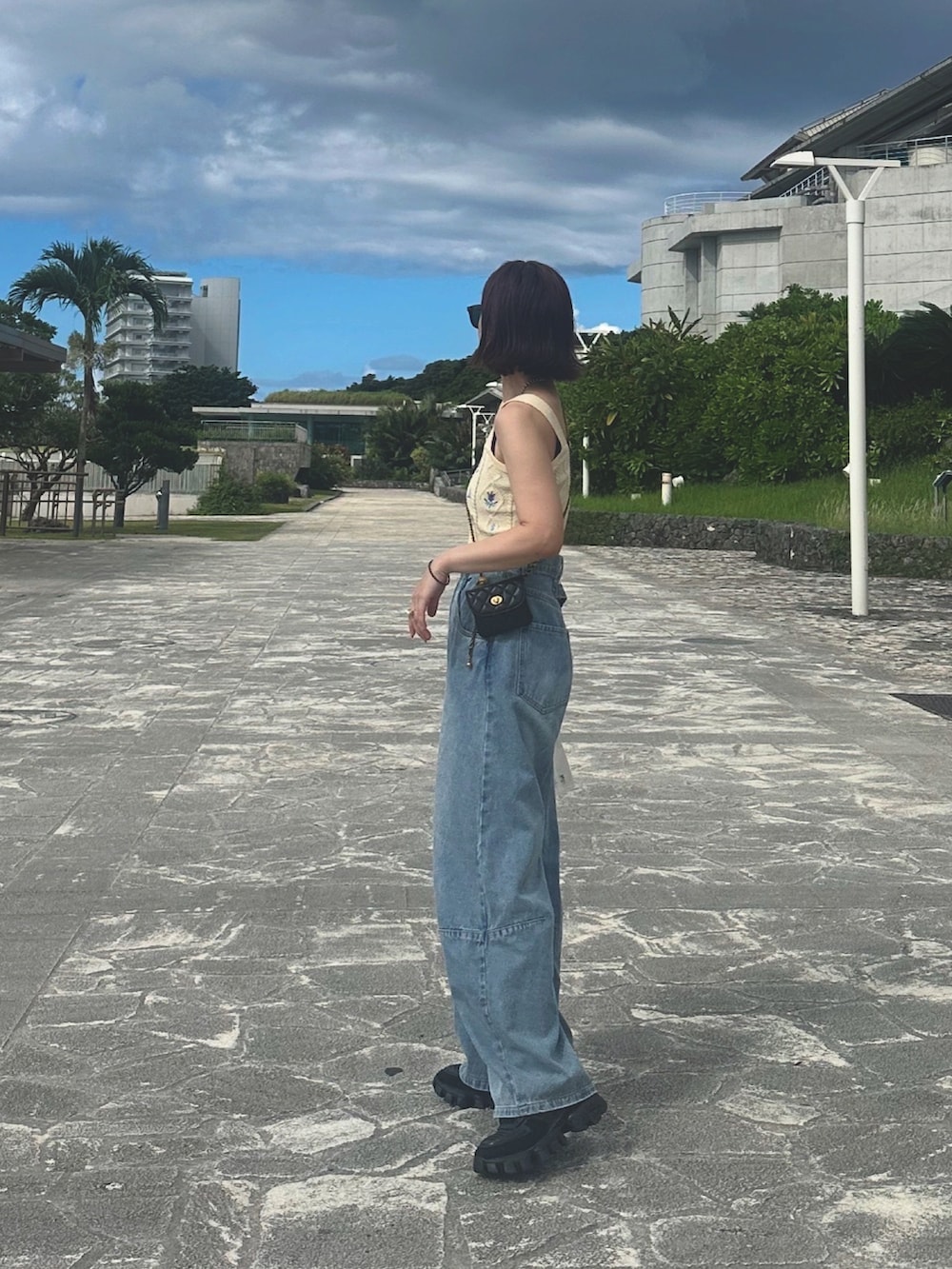 ブルー系のデニムパンツ、ブラック系のバッグ、ブラック系のスニーカーを着用したレディースの秋コーディネートの2枚目の写真