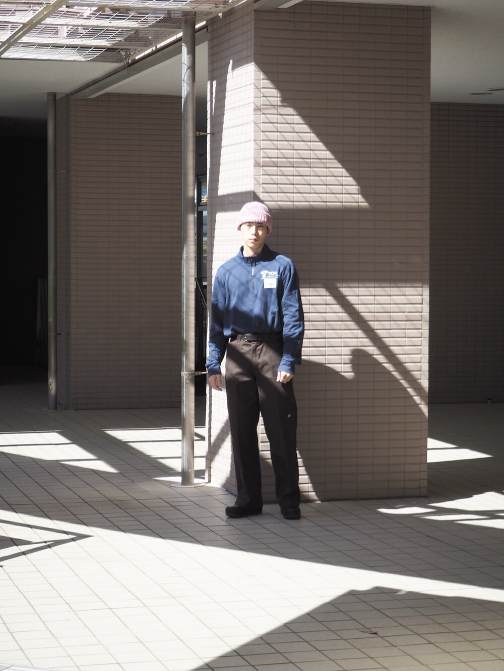 ブラウン系のチノパンツ、ブルー系のトップス、ブラック系のスリッポンを着用したメンズの春コーディネートの2枚目の写真