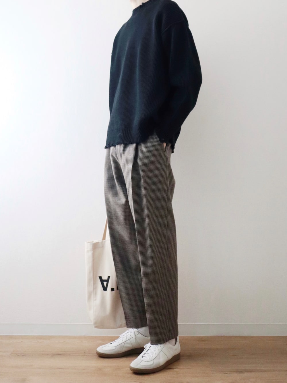 ブラック系のニット/セーター、ベージュ系のスラックス、ホワイト系のスニーカーを着用したメンズの秋コーディネートの3枚目の写真