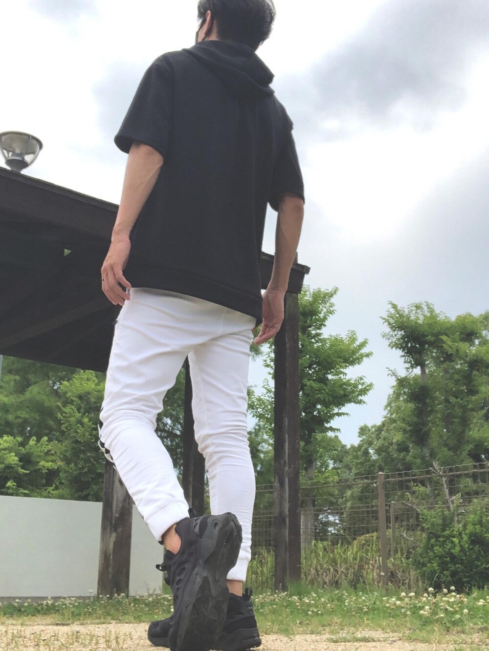 ブラック系のパーカー、ホワイト系のパンツ、ブラック系のスニーカーを着用したメンズの夏コーディネートの3枚目の写真