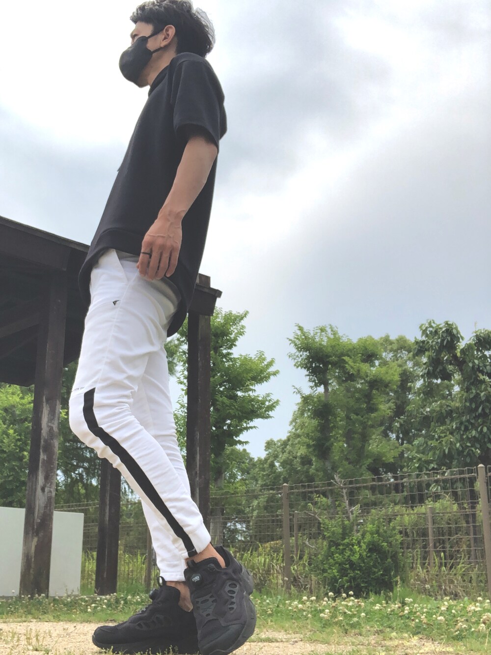 ブラック系のパーカー、ホワイト系のパンツ、ブラック系のスニーカーを着用したメンズの夏コーディネートの2枚目の写真