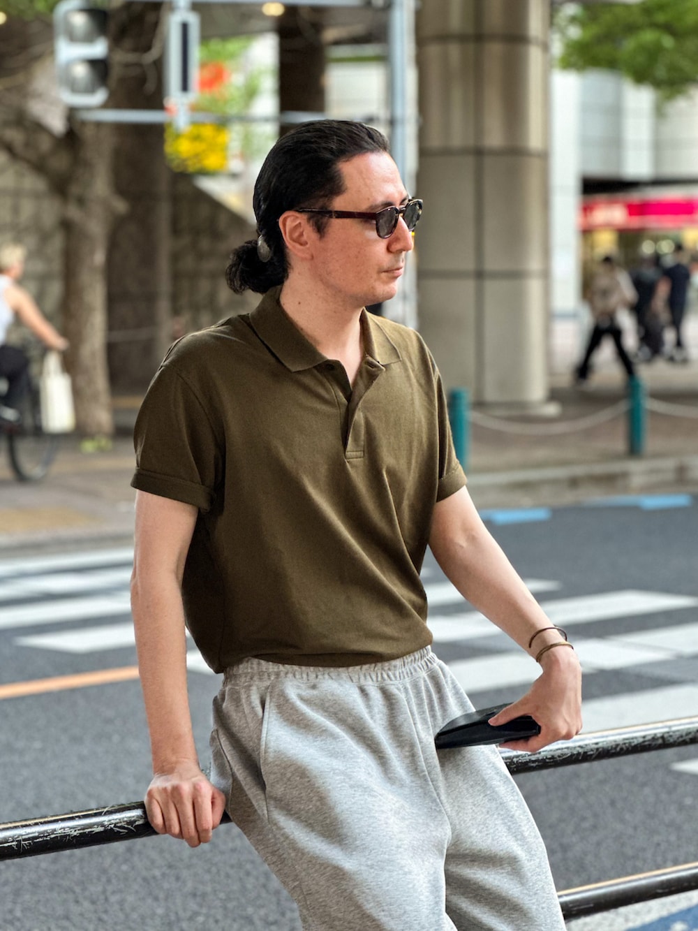 グレー系のスウェットパンツ、ブラック系のスニーカー、グリーン系のポロシャツを着用したメンズの春コーディネートの2枚目の写真