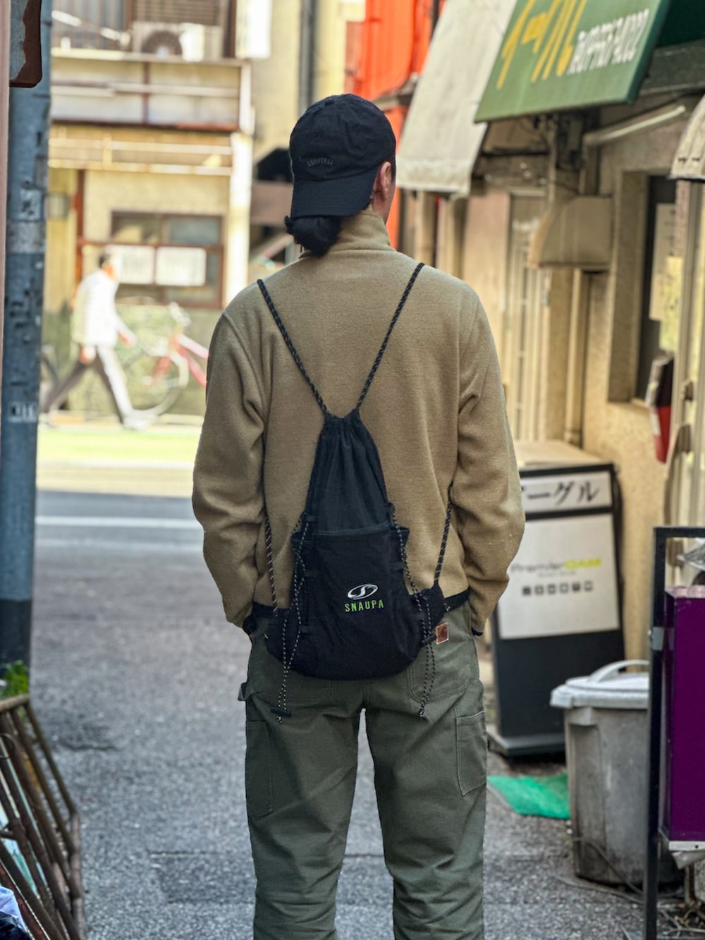 グリーン系のデニムパンツ、ベージュ系のその他アウター、グレー系のスニーカーを着用したメンズの春コーディネートの2枚目の写真