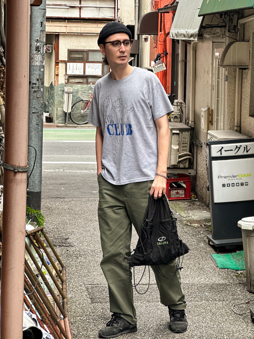 グレー系のTシャツ/カットソー、グリーン系のデニムパンツ、ブラック系のエコバッグ/サブバッグを着用したメンズの秋コーディネートの3枚目の写真