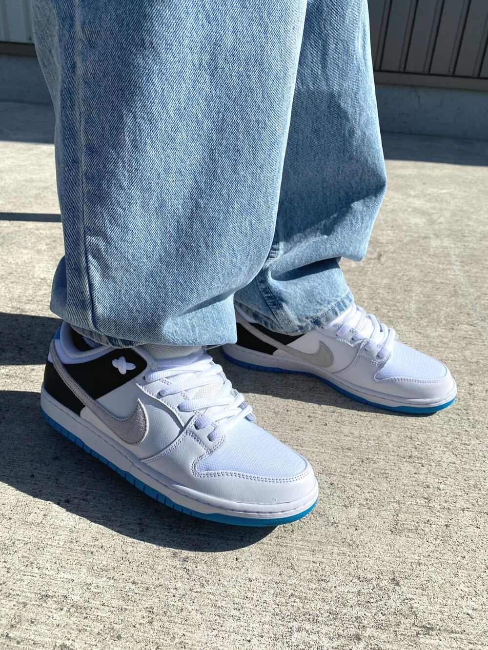 ホワイト系のスニーカー、ブルー系のデニムパンツ、ベージュ系のTシャツ/カットソーを着用したメンズの秋コーディネートの2枚目の写真