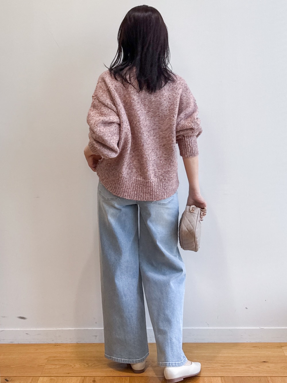 ピンク系のニット/セーター、ブルー系のデニムパンツ、ベージュ系のショルダーバッグを着用したレディースの夏コーディネートの3枚目の写真