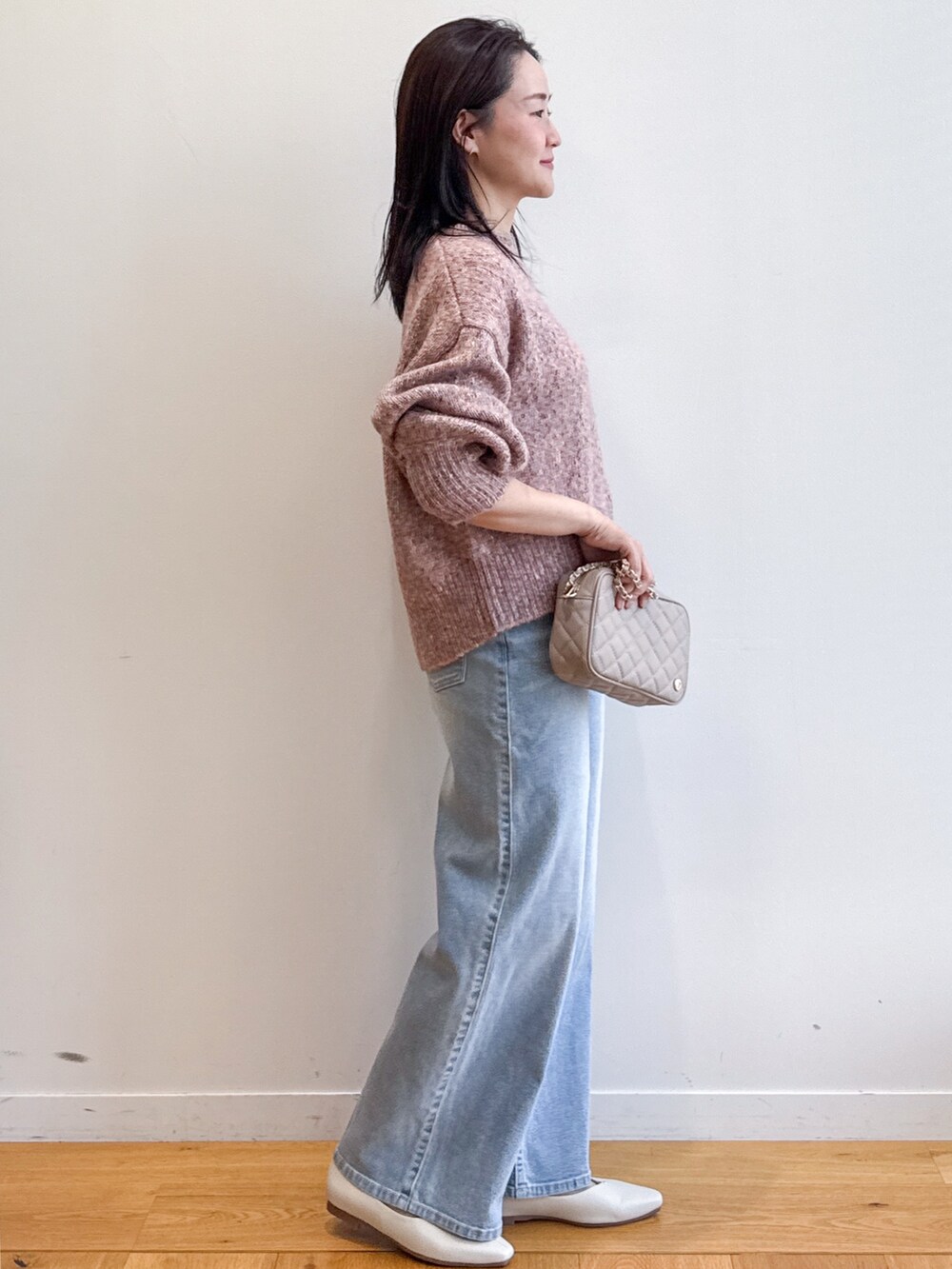 ピンク系のニット/セーター、ブルー系のデニムパンツ、ベージュ系のショルダーバッグを着用したレディースの夏コーディネートの2枚目の写真