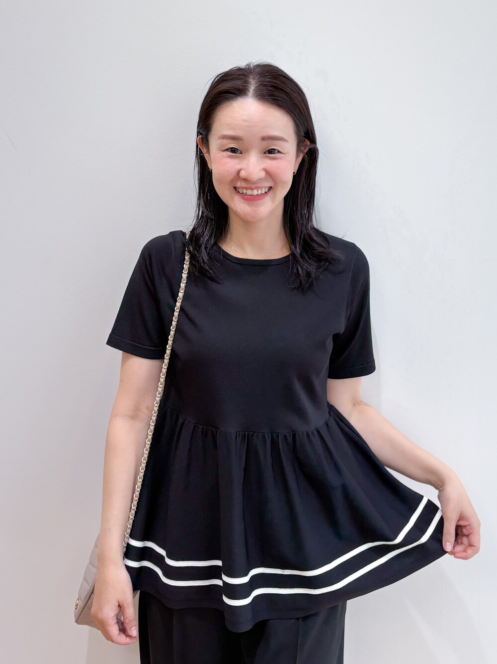 ブラック系のニット/セーター、ブラック系のその他パンツ、ベージュ系のショルダーバッグを着用したレディースの夏コーディネートの4枚目の写真