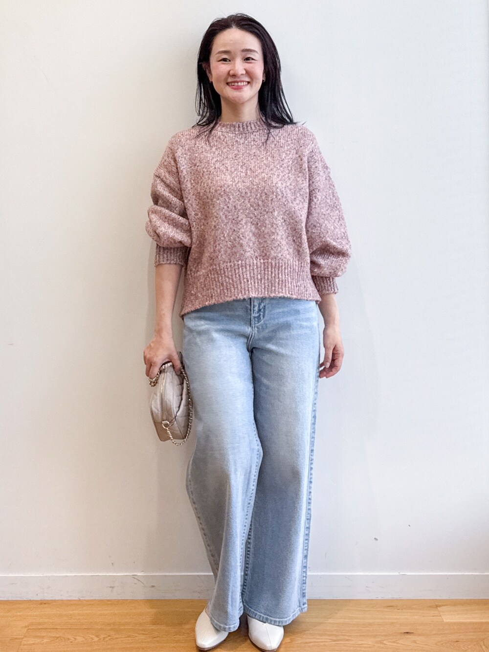 ピンク系のニット/セーター、ブルー系のデニムパンツ、ベージュ系のショルダーバッグを着用したレディースの夏コーディネートの4枚目の写真