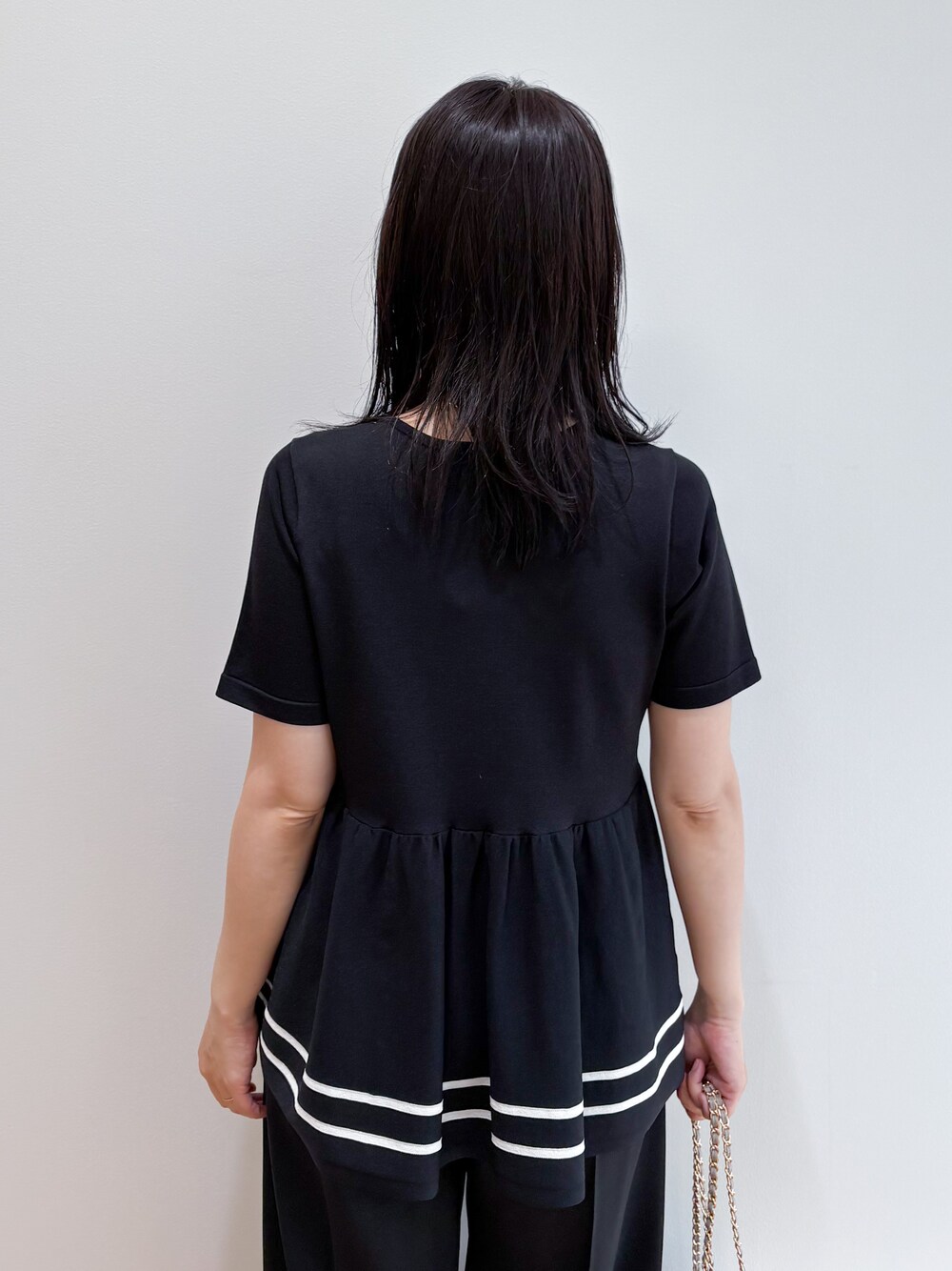 ブラック系のニット/セーター、ブラック系のその他パンツ、ベージュ系のショルダーバッグを着用したレディースの夏コーディネートの6枚目の写真