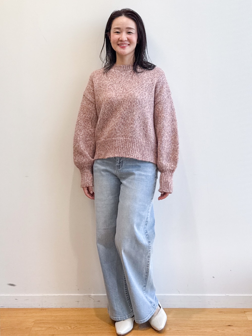 ピンク系のニット/セーター、ブルー系のデニムパンツ、ベージュ系のショルダーバッグを着用したレディースの夏コーディネートの5枚目の写真