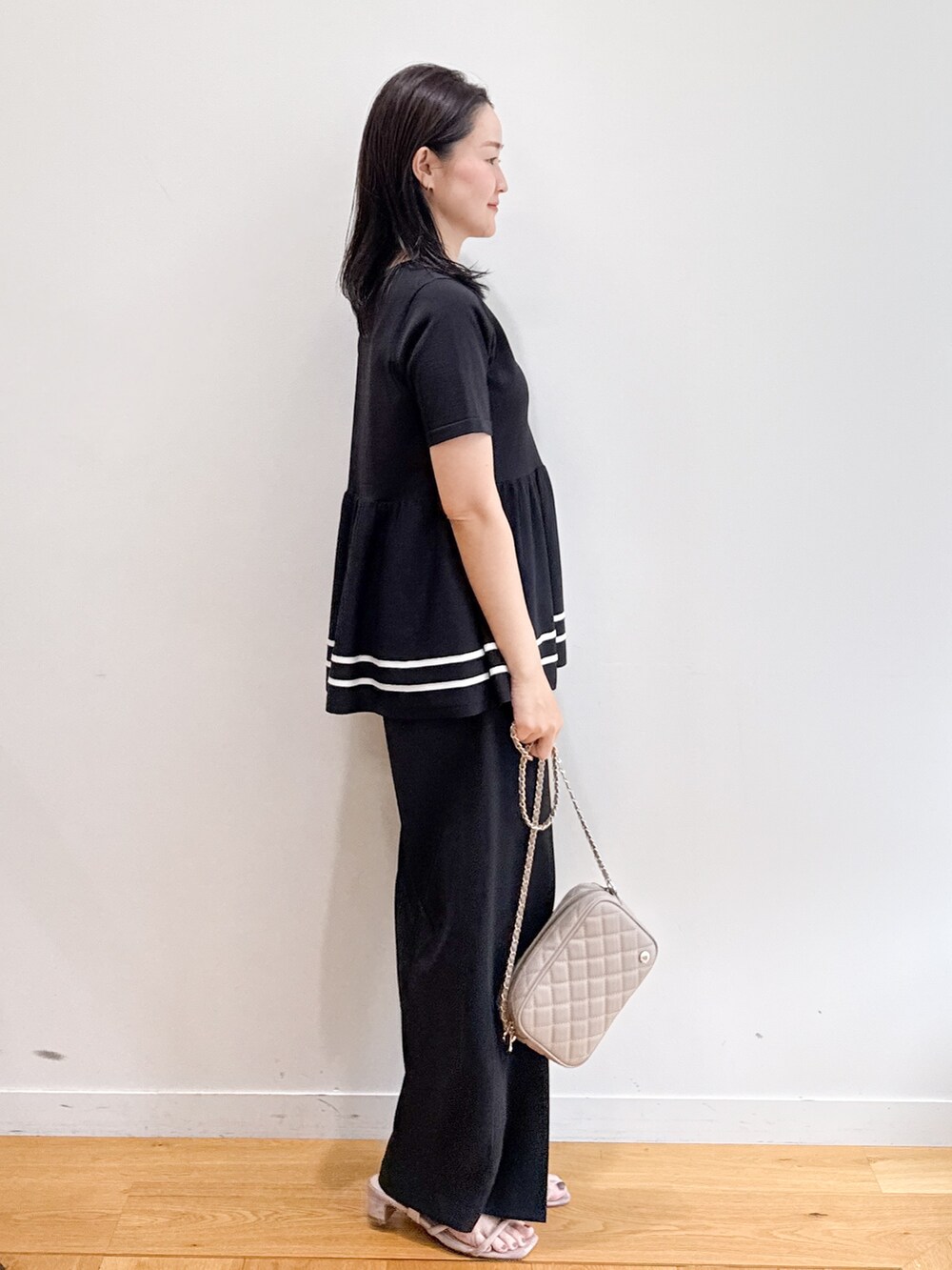 ブラック系のニット/セーター、ブラック系のその他パンツ、ベージュ系のショルダーバッグを着用したレディースの夏コーディネートの2枚目の写真