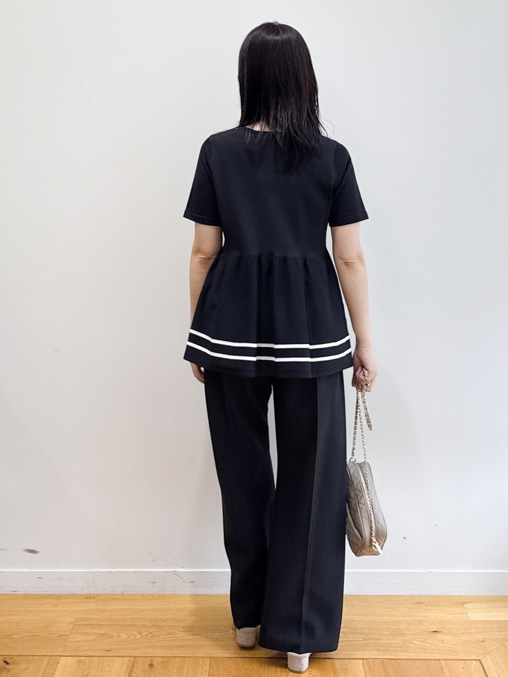 ブラック系のニット/セーター、ブラック系のその他パンツ、ベージュ系のショルダーバッグを着用したレディースの夏コーディネートの3枚目の写真