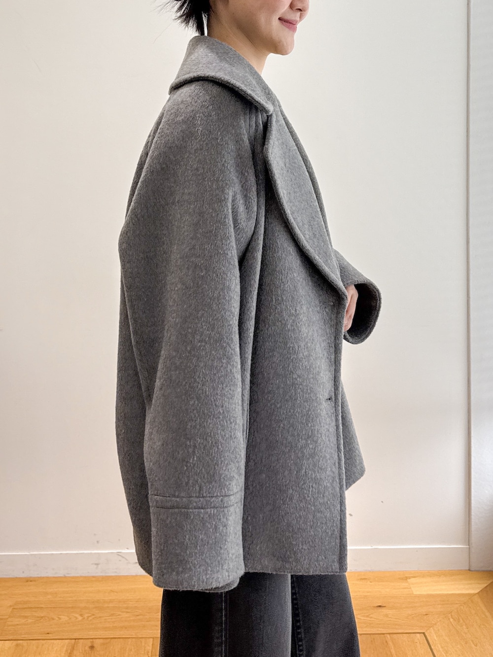グレー系のピーコート、ブラック系のデニムパンツ、ベージュ系のパンプスを着用したレディースの秋コーディネートの5枚目の写真