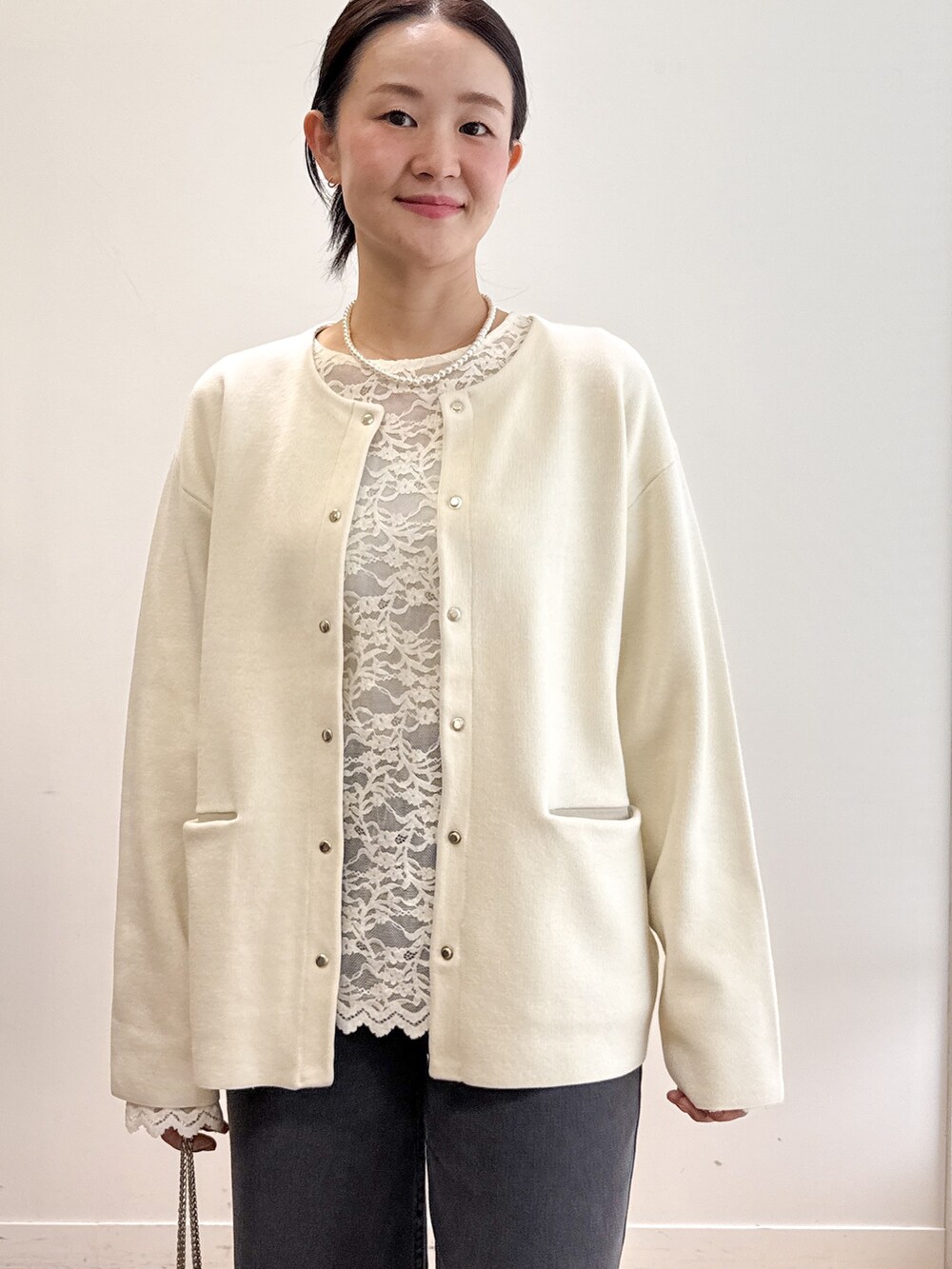ホワイト系のカーディガン/ボレロ、ホワイト系のTシャツ/カットソー、ブラック系のデニムパンツを着用したレディースの秋コーディネートの4枚目の写真