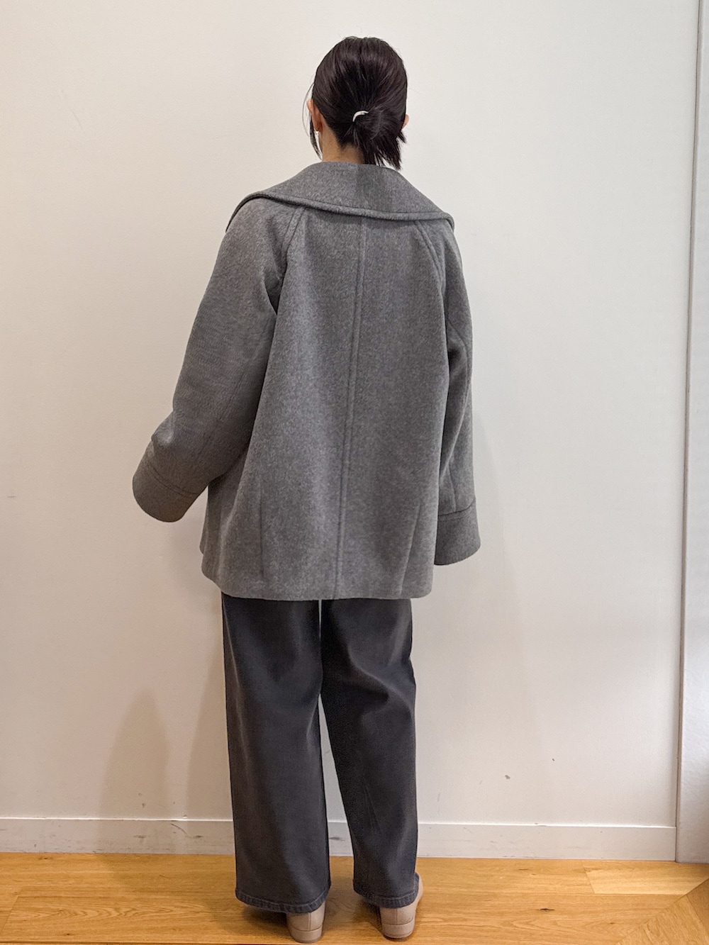 グレー系のピーコート、ブラック系のデニムパンツ、ベージュ系のパンプスを着用したレディースの秋コーディネートの3枚目の写真
