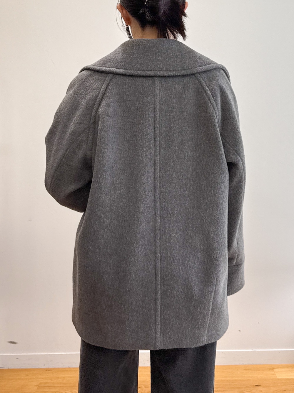 グレー系のピーコート、ブラック系のデニムパンツ、ベージュ系のパンプスを着用したレディースの秋コーディネートの6枚目の写真