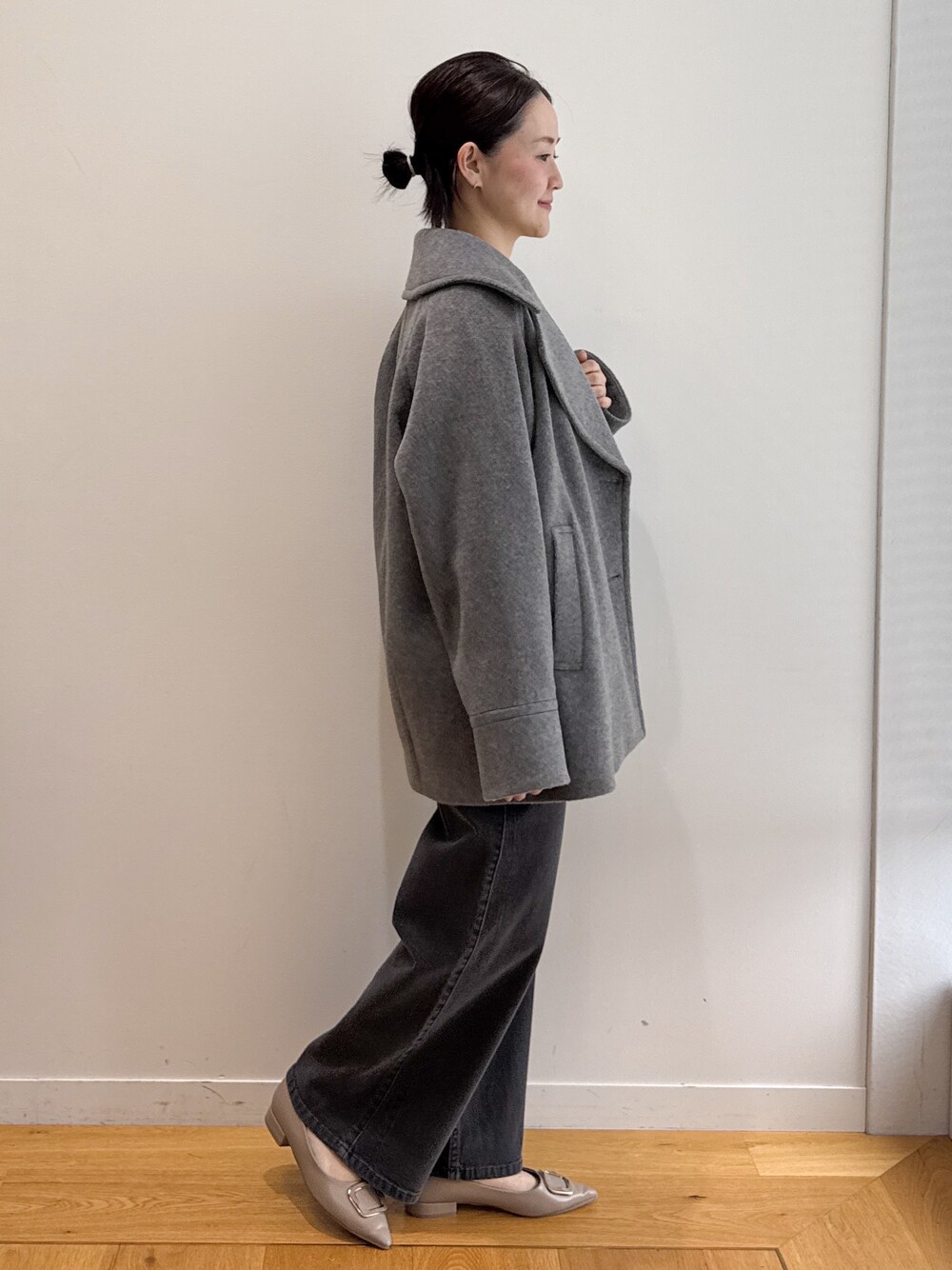 グレー系のピーコート、ブラック系のデニムパンツ、ベージュ系のパンプスを着用したレディースの秋コーディネートの2枚目の写真