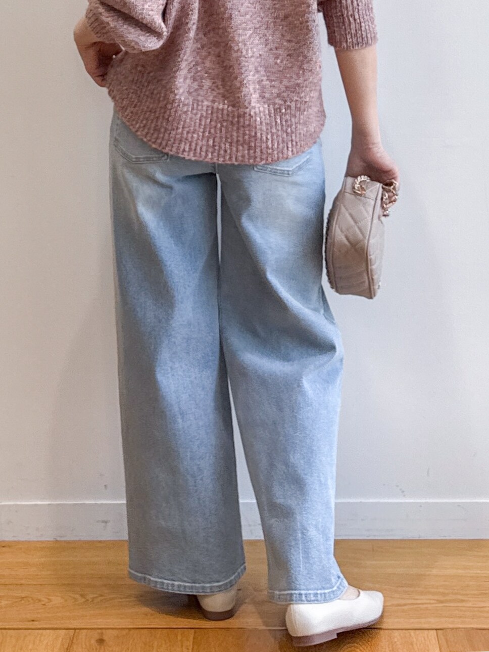 ピンク系のニット/セーター、ブルー系のデニムパンツ、ベージュ系のショルダーバッグを着用したレディースの夏コーディネートの8枚目の写真