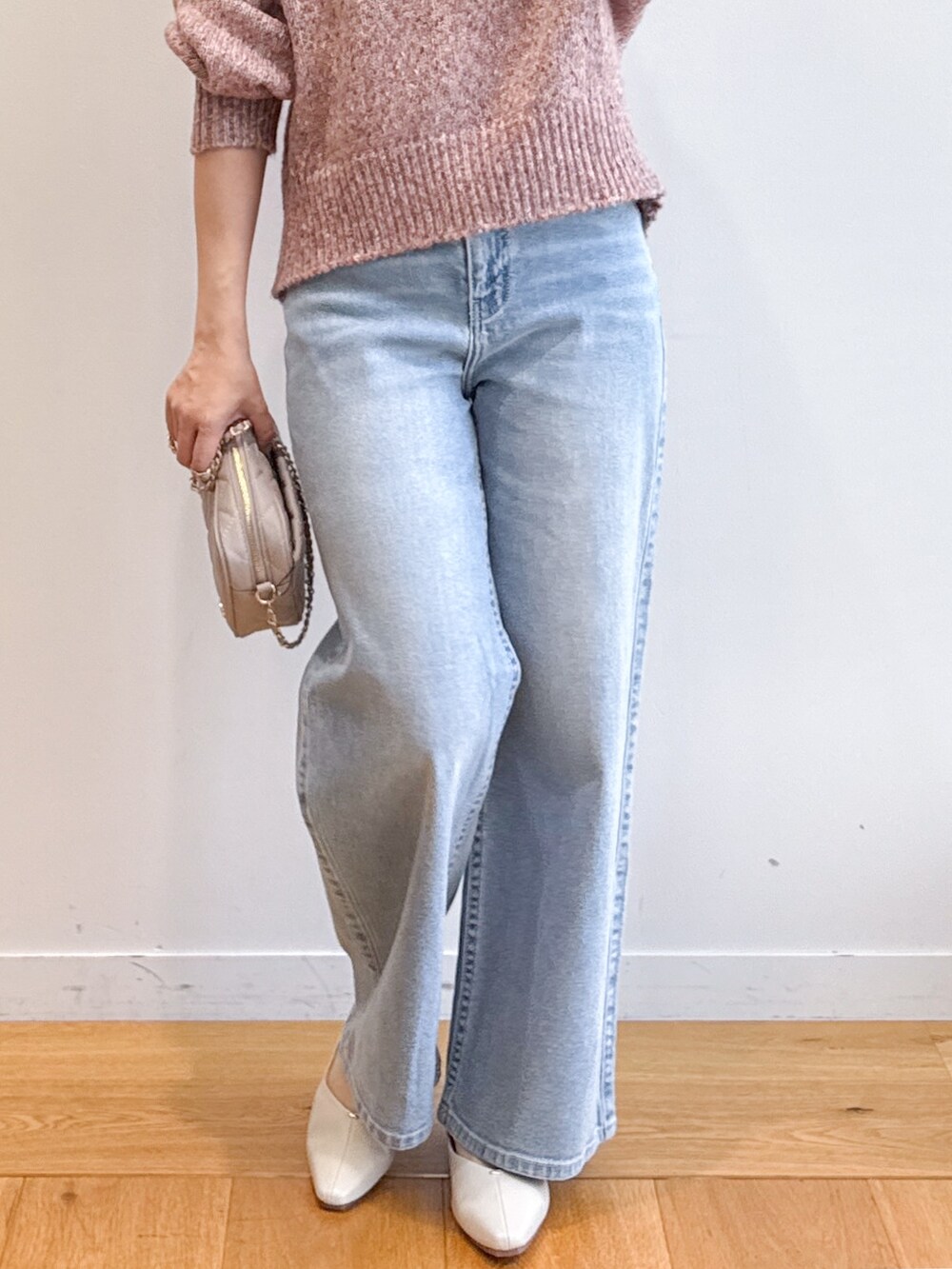 ピンク系のニット/セーター、ブルー系のデニムパンツ、ベージュ系のショルダーバッグを着用したレディースの夏コーディネートの7枚目の写真