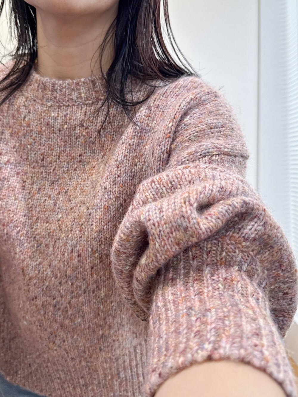 ピンク系のニット/セーター、ブルー系のデニムパンツ、ベージュ系のショルダーバッグを着用したレディースの夏コーディネートの6枚目の写真