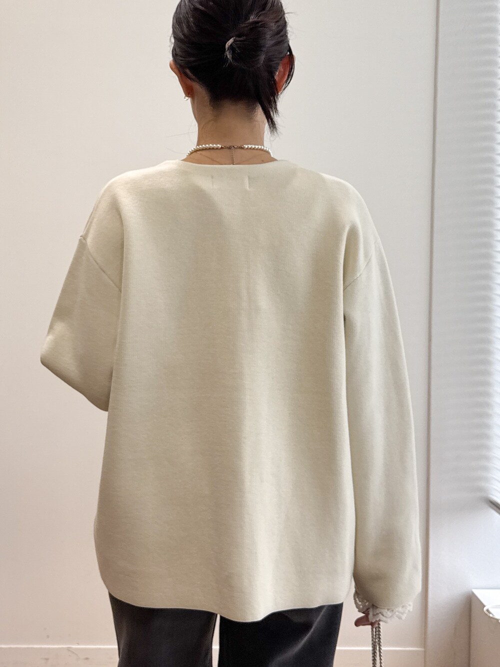 ホワイト系のカーディガン/ボレロ、ホワイト系のTシャツ/カットソー、ブラック系のデニムパンツを着用したレディースの秋コーディネートの6枚目の写真