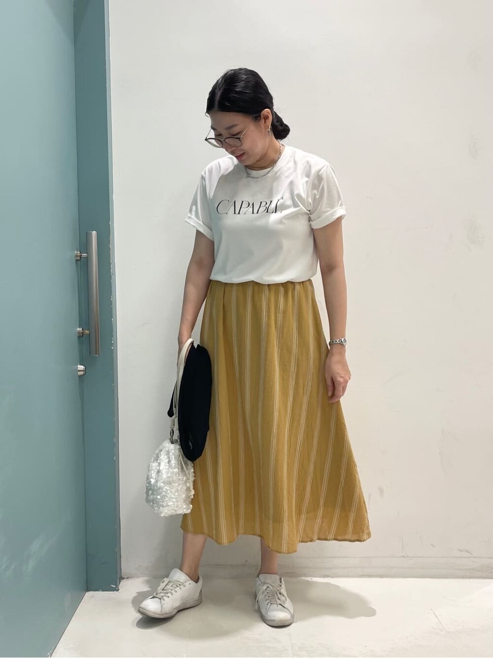 ブラック系のカーディガン/ボレロ、ホワイト系のTシャツ/カットソー、イエロー系のスカートを着用したレディースの夏コーディネートの4枚目の写真