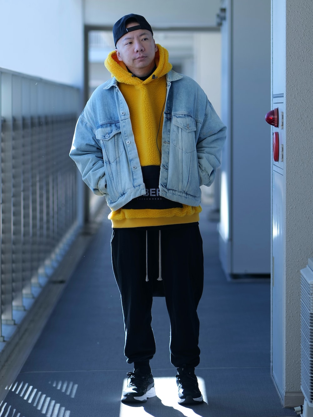 イエロー系のブルゾン、ブラック系のTシャツ/カットソー、ブラック系のスウェットパンツを着用したメンズの冬コーディネートの2枚目の写真