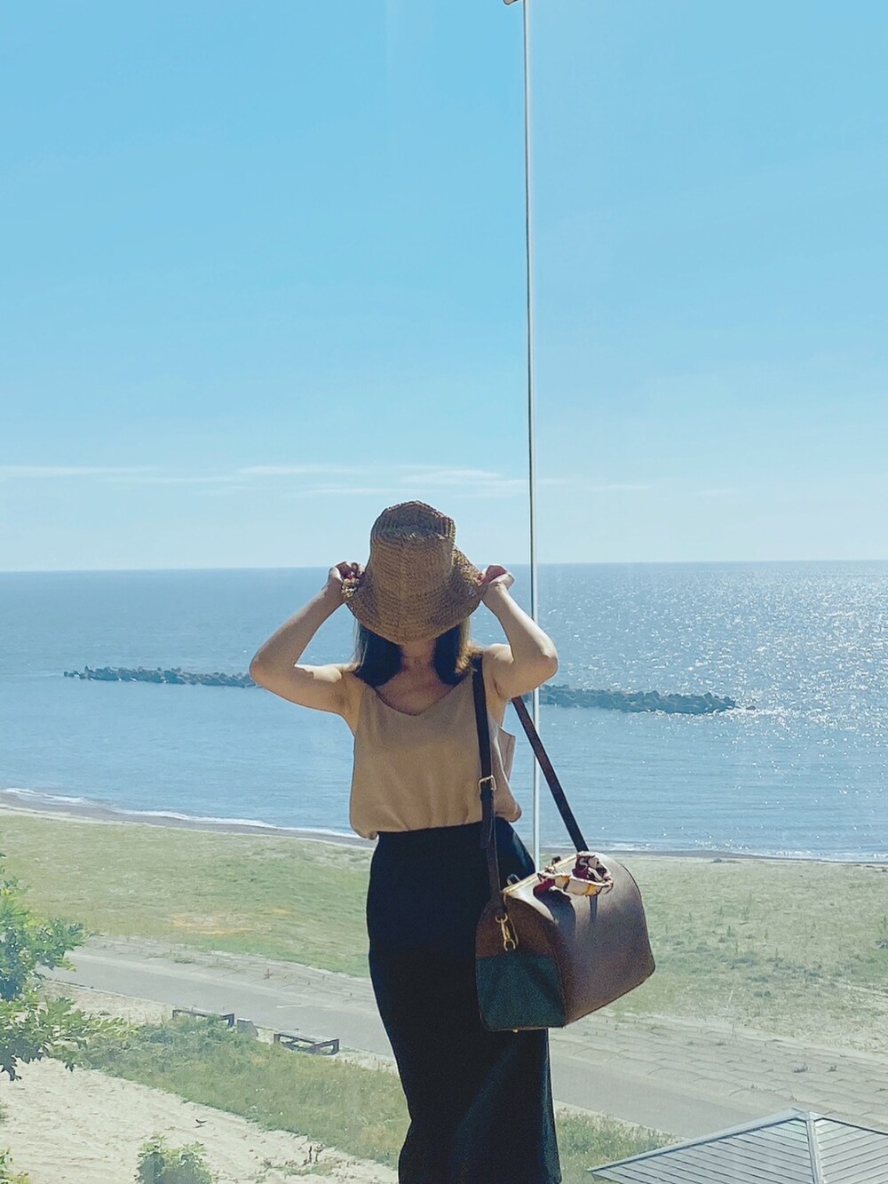 ブラウン系のボストンバッグ、ベージュ系のキャミソール、ブラック系のスカートを着用したレディースの夏コーディネートの2枚目の写真