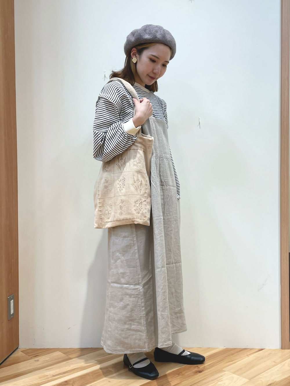 ベージュ系のワンピース、ホワイト系のトップス、ベージュ系のトートバッグを着用したレディースの秋コーディネートの2枚目の写真