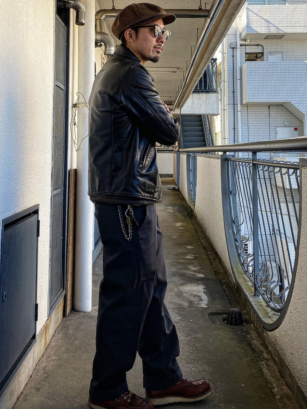 ブラック系のライダースジャケット、グレー系のチノパンツ、レッド系のブーツを着用したメンズの冬コーディネートの2枚目の写真