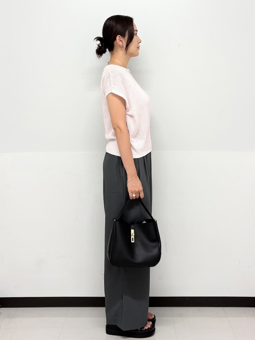 ピンク系のニット/セーター、グレー系のその他パンツ、ブラック系のトートバッグを着用したレディースの夏コーディネートの3枚目の写真