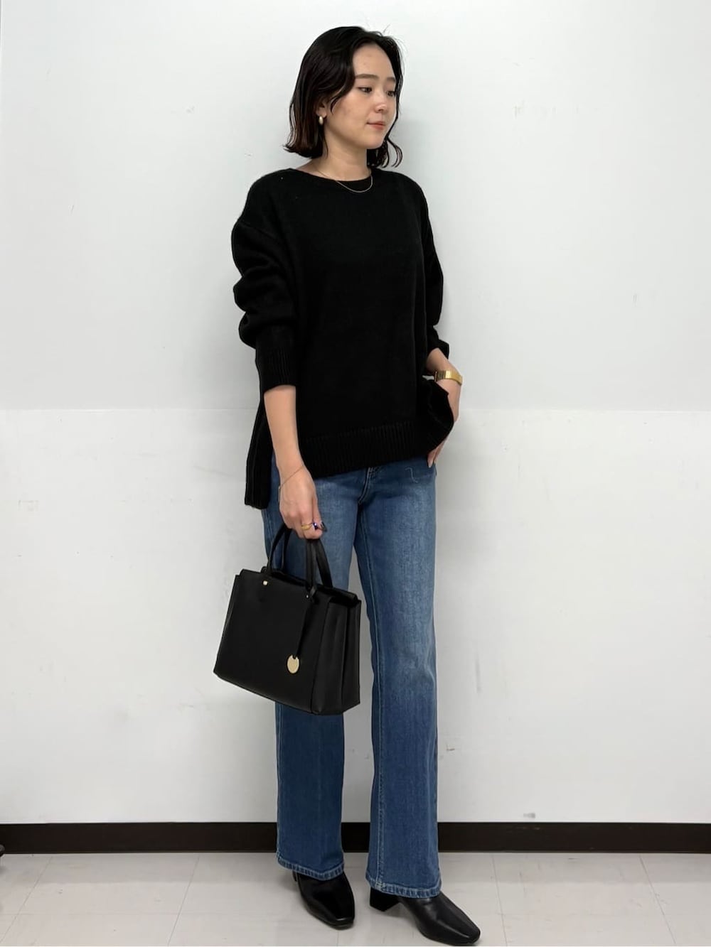 ブラック系のニット/セーター、ブルー系のデニムパンツ、ブラック系のトートバッグを着用したレディースの冬コーディネートの2枚目の写真