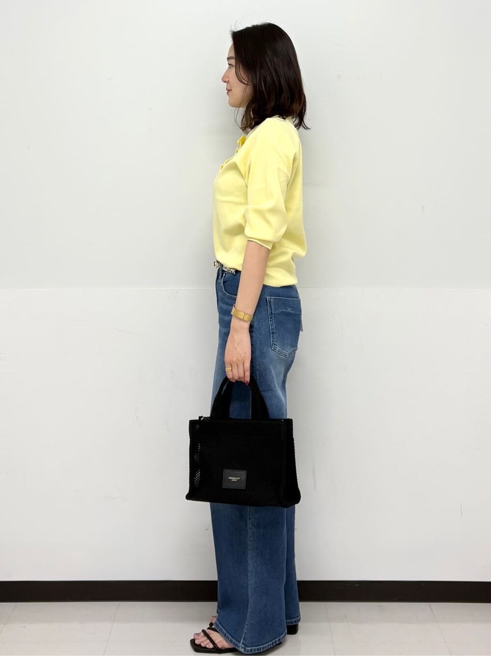 イエロー系のニット/セーター、ブルー系のデニムパンツ、ブラック系のトートバッグを着用したレディースの春コーディネートの3枚目の写真
