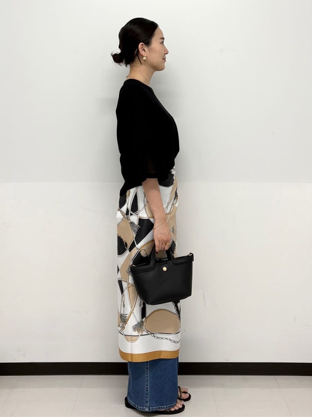 ブルー系のデニムパンツ、ブラック系のショルダーバッグ、シルバー系のサンダルを着用したレディースの春コーディネートの3枚目の写真